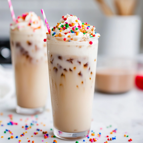 Freshly brewed espresso being poured into an iced latte with almond milk and sugar cookie syrup.