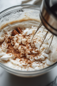 A blender or large mixing bowl filled with pumpkin purée, coconut milk, brown sugar, cornstarch, maple syrup, vanilla extract, pumpkin pie spice, cinnamon, and salt. A hand mixer or whisk is blending the ingredients into a smooth, creamy filling