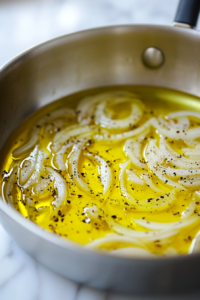 The saucepan on the white marble cooktop, now filled with golden brown onions after 30 minutes of cooking. The onions are caramelized and fragrant, with a rich color