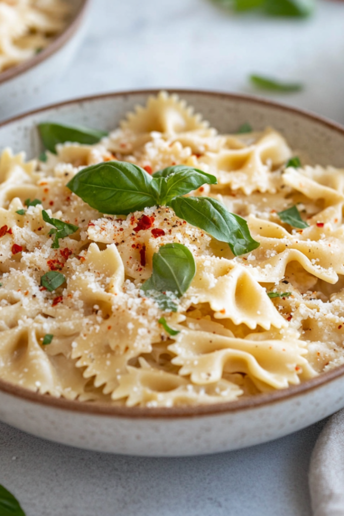 Wide shot of a table set with bowls of creamy coconut milk pasta, topped with fresh basil, red pepper flakes, and extra vegan parmesan. The dish is warm and inviting, ready to be enjoyed.