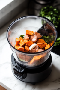 A high-speed blender with roasted sweet potatoes, shallots, garlic, and hot chicken stock blended to a smooth consistency. The blend looks creamy and vibrant, ready to be transformed into a delicious sauce.