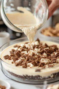 Close-up shot of a spatula folding chopped frosted animal cookies into the cheesecake batter, ensuring an even distribution without over-mixing.