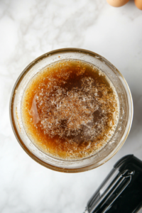 A stand mixer blending browned butter, shortening, sugar, eggs, vanilla, and sour cream into a smooth batter.