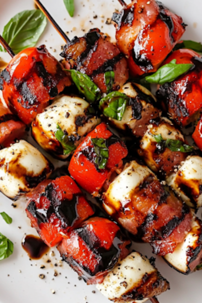 A close-up shot of the final caprese bacon skewers dish, beautifully drizzled with balsamic glaze and sprinkled with fresh cracked black pepper, served on a plate with a glossy sheen from the oil and pesto, all set on the white marble cooktop, ready to be enjoyed.