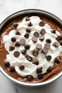 A chocolate mug cake served next to a glass of Iced Sugar Cookie Almond Milk Latte on a white marble cooktop. The rich, chocolatey dessert and the creamy, iced drink create an indulgent and inviting pairing.