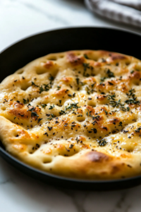 A spatula flipping the golden-brown flatbread in the black non-stick skillet over the white marble cooktop, revealing its crispy, slightly textured surface.