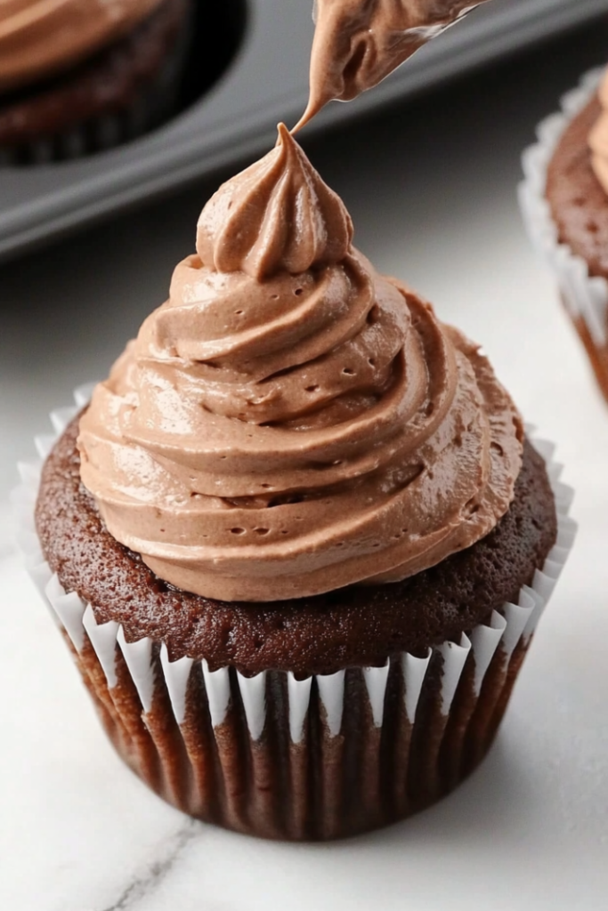 A close-up shot of a piping bag filled with chocolate whipped cream, being swirled on top of each mini cheesecake.