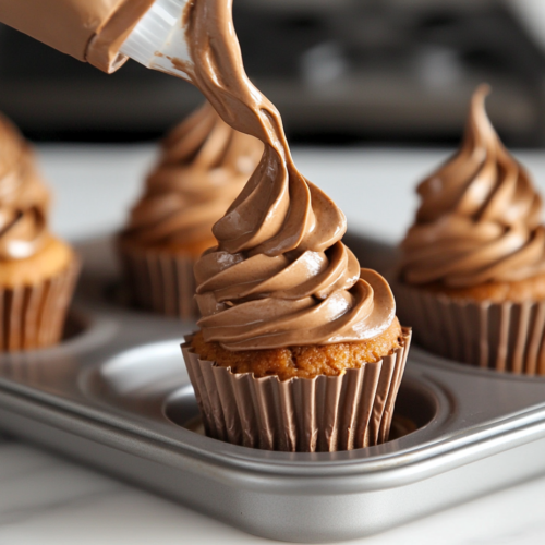 A close-up shot of a piping bag filled with chocolate whipped cream, being swirled on top of each mini cheesecake.