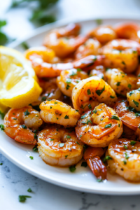 A close-up shot of a serving plate over the white marble cooktop, filled with sugar-free honey butter shrimp, garnished with fresh herbs and lemon wedges. The shrimp are glistening in the rich, caramelized sauce, ready to be enjoyed.