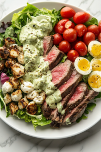 A close-up of a white ceramic serving plate on a white marble cooktop, featuring a beautifully arranged steak Cobb salad. A drizzle of creamy avocado dressing cascades over the vibrant fresh ingredients, ready to be enjoyed.