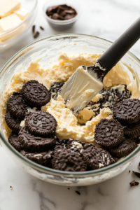 A bowl filled with finely crushed chocolate sandwich cookies, ready to be mixed with melted butter for the cheesecake crust