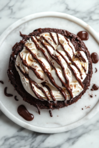 Close-up shot of the 10-inch black pie pan on the white marble cooktop, filled with smooth brownie batter spread evenly over the pre-baked crust. The pan is being placed into the preheated oven.