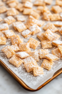 A baking sheet with pink sugar-coated Chex cereal spread out to dry.