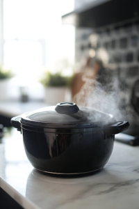 A black slow cooker on a white marble cooktop, now covered and slowly cooking, as steam lightly rises from the edges, letting the flavors blend into a rich and creamy dish.