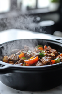 A black slow cooker on a white marble cooktop, now covered and cooking, with steam slightly fogging up the lid as the fajita ingredients slowly meld together, releasing mouthwatering aromas.