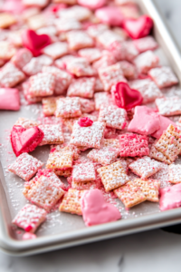 A baking sheet with both pink and red sugar-coated Chex cereal drying, ready to serve.