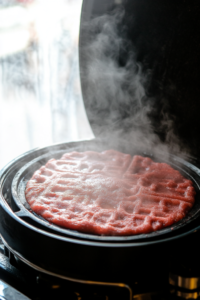 A pancake sizzling on a non-stick skillet, with bubbles forming on top, ready to be flipped for even cooking.