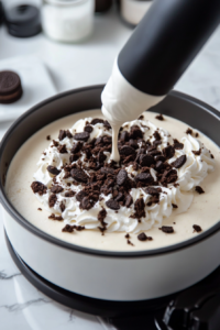The chilled Oreo cheesecake topped with piped whipped cream, additional crushed Oreos, and a drizzle of hot fudge.