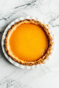 Overhead shot of a graham cracker pie crust with peach sauce over it