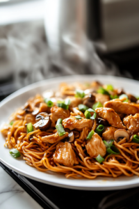 A serving plate on a white marble cooktop, piled high with sesame soy chicken and mushroom noodles. Steam rises from the dish, showcasing the glossy, flavorful noodles ready to be enjoyed.