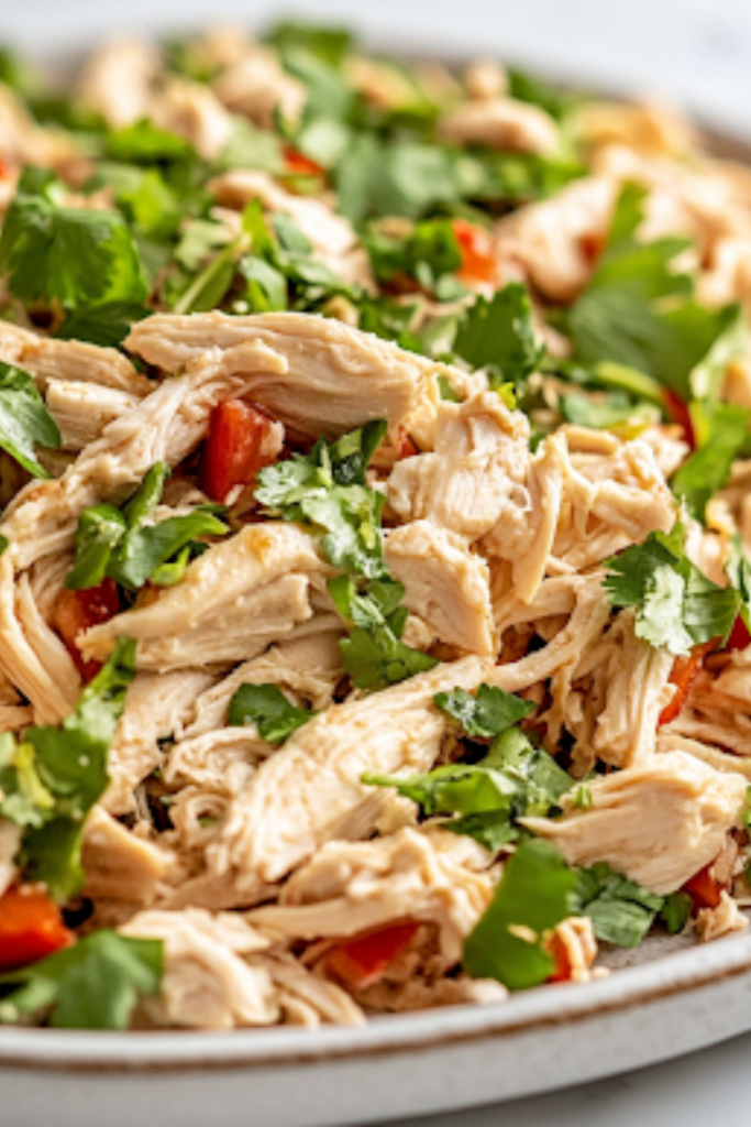 A serving plate on a white marble cooktop showcases the fully mixed Chinese Chicken Salad, bursting with crisp textures and vibrant colors. Fresh herbs garnish the dish, making it ready to be served.