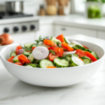A close-up view of the sweet and tangy cucumber onion salad served in a white ceramic bowl on a white marble cooktop. The glossy, chilled vegetables glisten under soft lighting, ready to be enjoyed as a refreshing side dish.