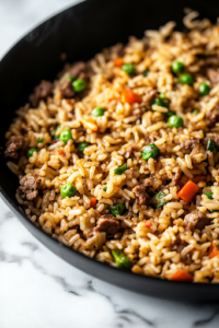 A close-up shot of a fork fluffing the dirty rice inside the black skillet on the white marble cooktop. The grains separate beautifully, with bits of seasoned meat and vegetables evenly distributed.