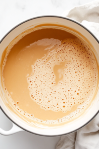 An overhead shot of a large mixing bowl where cream cheese and sugar are being beaten together until smooth and creamy. The texture is rich and velvety.
