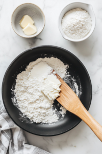 Flour is added to the skillet to make a roux, cooking for about one minute. This thickens the sauce and adds a smooth texture to the creamy garlic sauce, which will envelop the salmon fillets for a perfect finish.