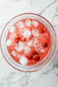 Ice cubes are added to the punch for immediate serving, ensuring the drink stays chilled. Alternatively, the punch can be refrigerated for an hour to allow the flavors to blend, enhancing the taste and making the drink more refreshing.