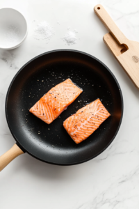 The salmon fillets are seared in a skillet until they reach a golden-brown crisp on both sides. The cooking process takes about 4-5 minutes per side, ensuring a deliciously tender inside with a crispy exterior.