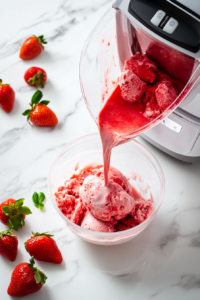 The strawberry ice cream mixture is poured into an ice cream maker, ready for churning. The ice cream maker transforms the mixture into a smooth and creamy texture, creating a delicious frozen dessert.