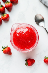 The blender is in motion, transforming frozen strawberries, vodka, sugar, and lime juice into a vibrant red slushy mixture. The texture is thick and icy, creating a perfectly chilled, refreshing frozen cocktail with a delicious balance of sweetness and citrus tang.