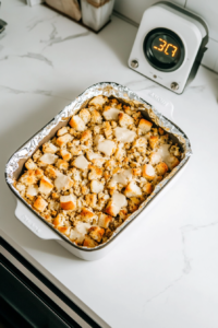 A baking dish filled with the prepared stuffing mixture, ready to be baked. The foil covering ensures the stuffing stays moist and evenly cooks during the first stage of baking before it is uncovered to achieve a crispy golden top.